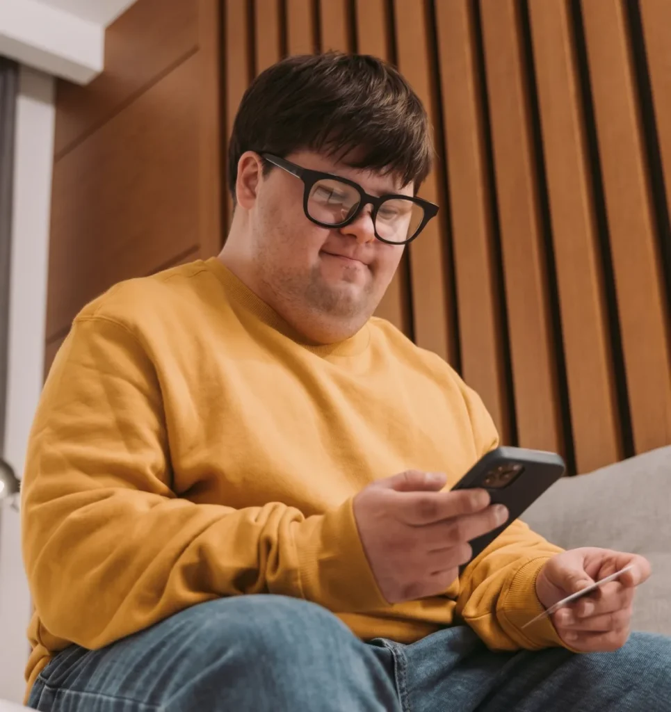 Smiling young man holding a phone and a credit card